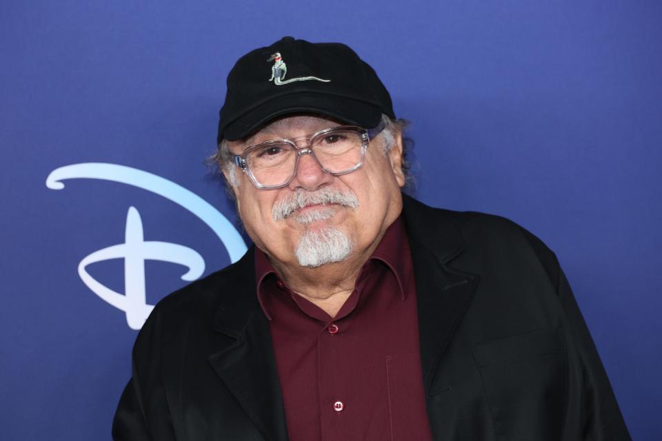 Danny DeVito  in a red shirt and black hat