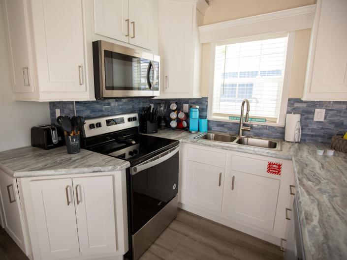 A full kitchen with countertop, stove, microwave, oven, sink, and cabinets.