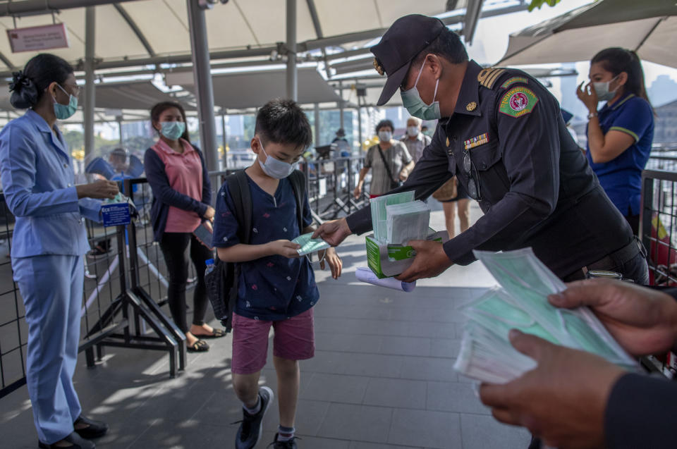 Health officials distribute protective face masks for visitors at a luxury mall in Bangkok, Thailand, Tuesday, Jan. 28, 2020. Panic and pollution drive the market for protective face masks, so business is booming in Asia, where fear of the coronavirus from China is straining supplies and helping make mask-wearing the new normal. (AP Photo/Gemunu Amarasinghe)