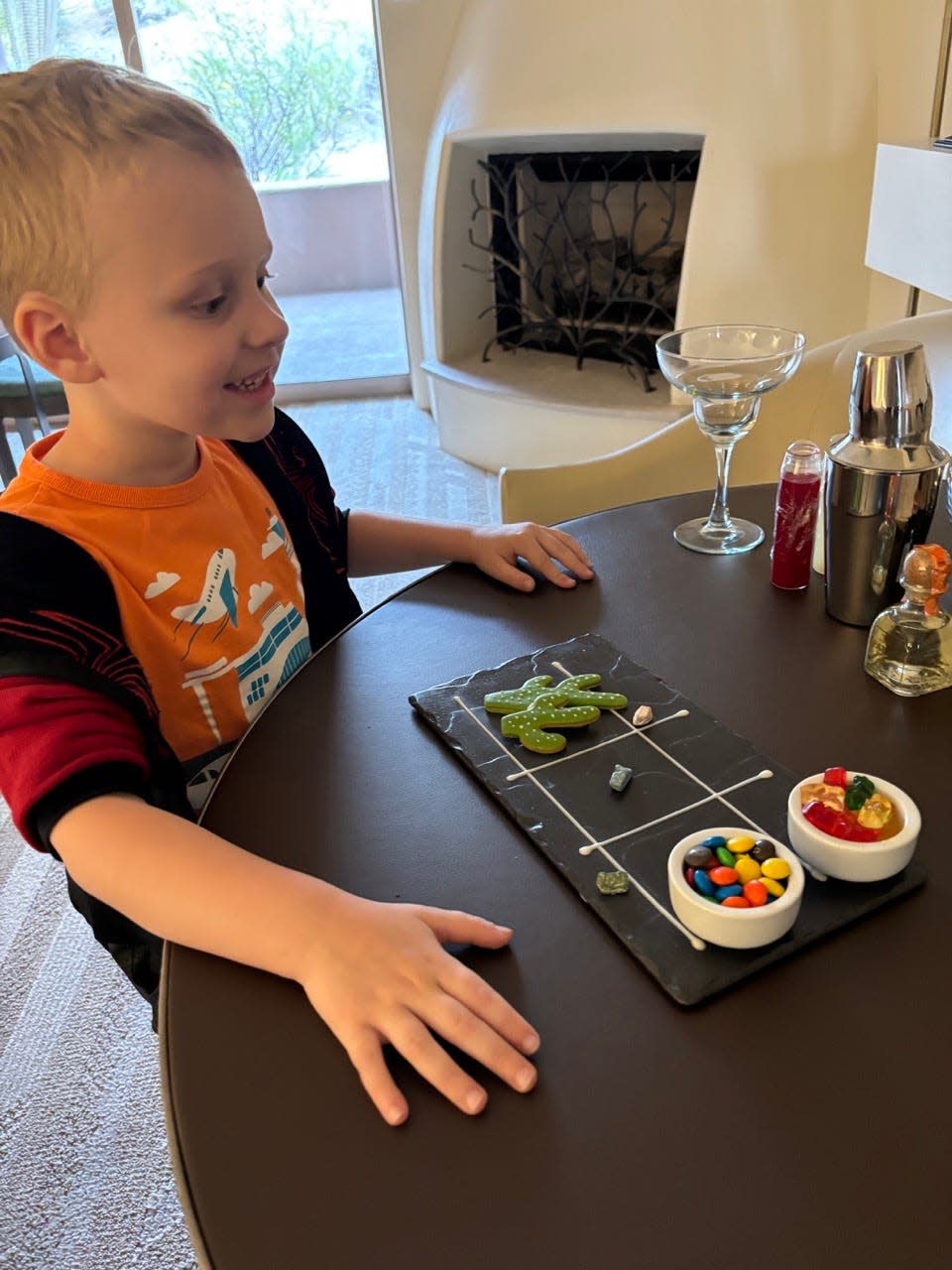 Child smiling in front of fireplace next to cactus-shaped cookies