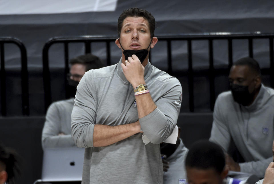 Luke Walton pulls down his face mask to yell calls to the team from the sideline.