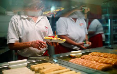 Employees sell "Currywurst" (curried sausage) in Berlin, Germany, August 27, 2016. During long nights out in Berlin, people get hungry. Snack stands are open all night long, and peckish party-goes find themselves faced with an important decision: Currywurst or doner kebab. REUTERS/Hannibal Hanschke