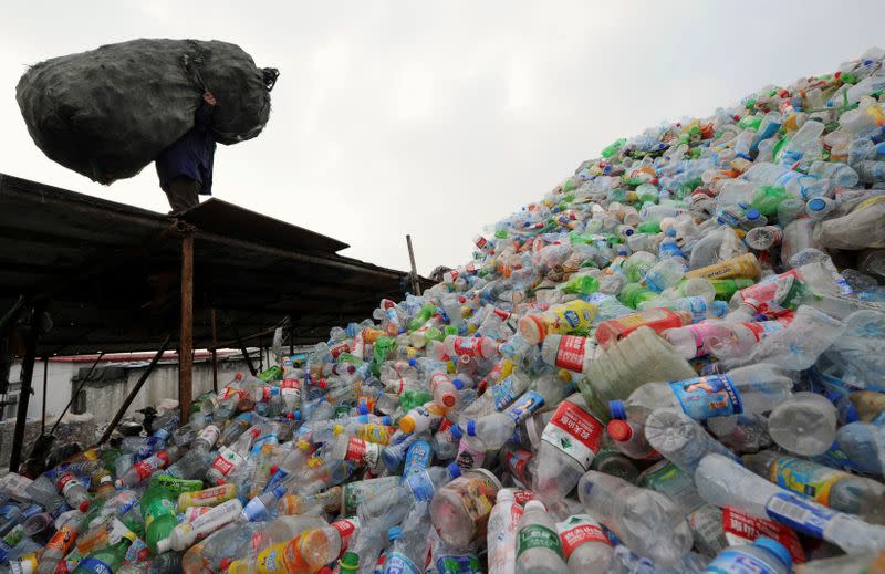 FILE PHOTO: A man carries a bag of plastic bottles on a roof at a recycling centre in Hefei