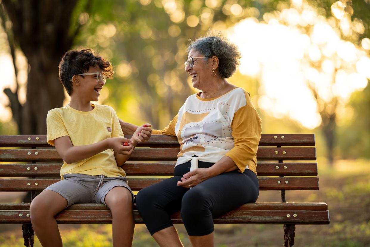 Grandmother and grandson are sitting in the park talking and smiling