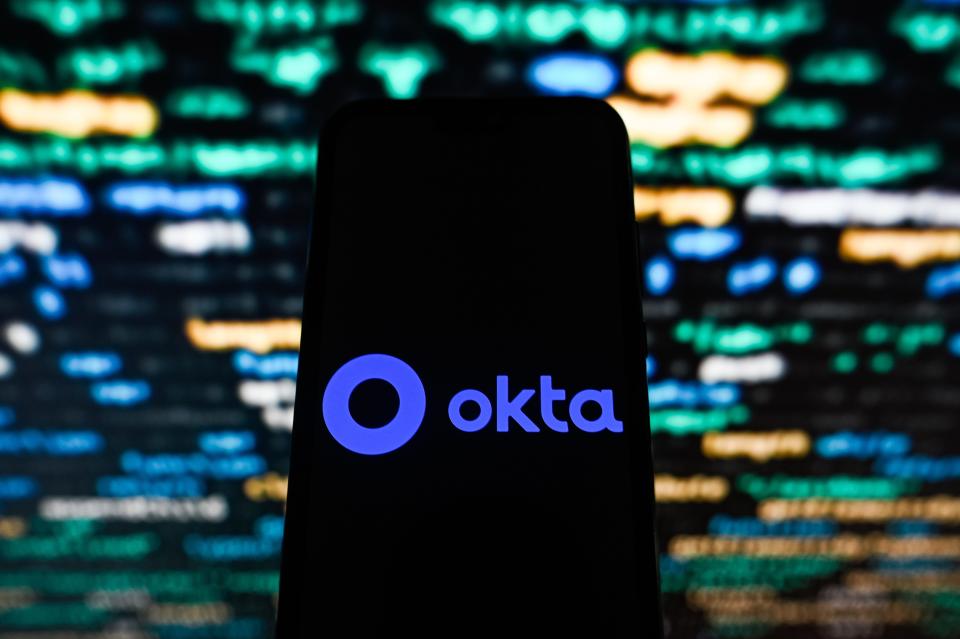 Okta logo displayed on a phone with bright lights in the background