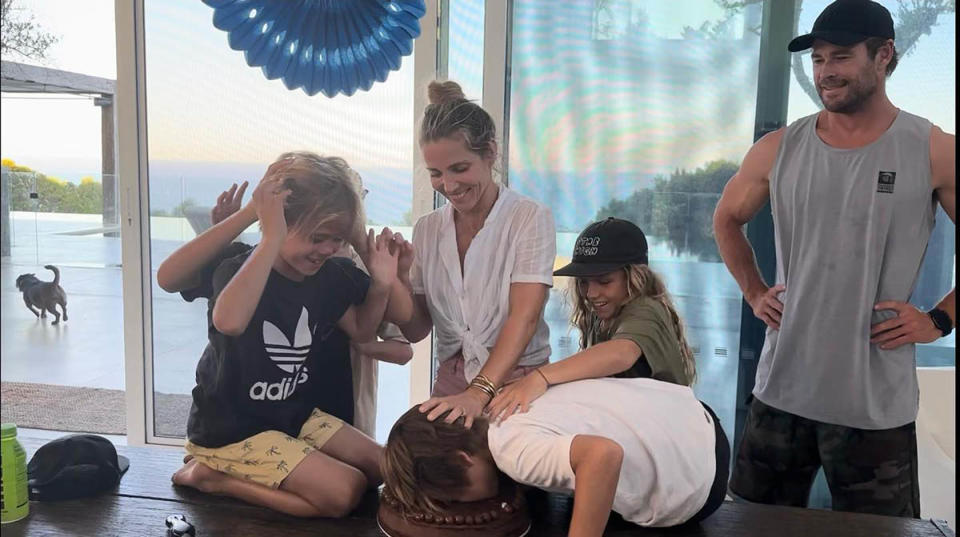 Chris Hemsworth, Elsa Pataky and their children. One son is being pushed into a chocolate cake