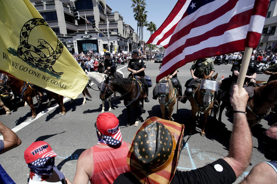 Law enforcement personnel on horseback keep protestors on the sidewalk during a May Day demonstration at the pier Friday, May 1, 2020, in Huntington Beach, Calif., during the coronavirus outbreak. (AP Photo/Chris Carlson)