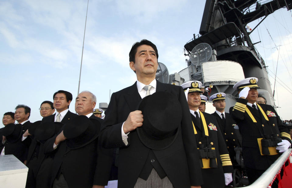 FILE - Then Japanese Prime Minister Shinzo Abe, center, and Director of Japan Self-Defense Force Fumio Kyuma, 5th left, salute while assisting at the Fleet Review of the Japan Maritime Self-Defense Force in Sagami Bay, off south Tokyo, Sunday, Oct. 29 2006. Former Japanese Prime Minister Abe, a divisive arch-conservative and one of his nation's most powerful and influential figures, has died after being shot during a campaign speech Friday, July 8, 2022, in western Japan, hospital officials said.(AP Photo/Franck Robichon, File)