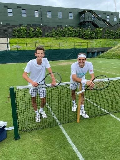 Nico Godsick, left, and Roger Federer pose on a tennis court at Wimbledon in 2021.