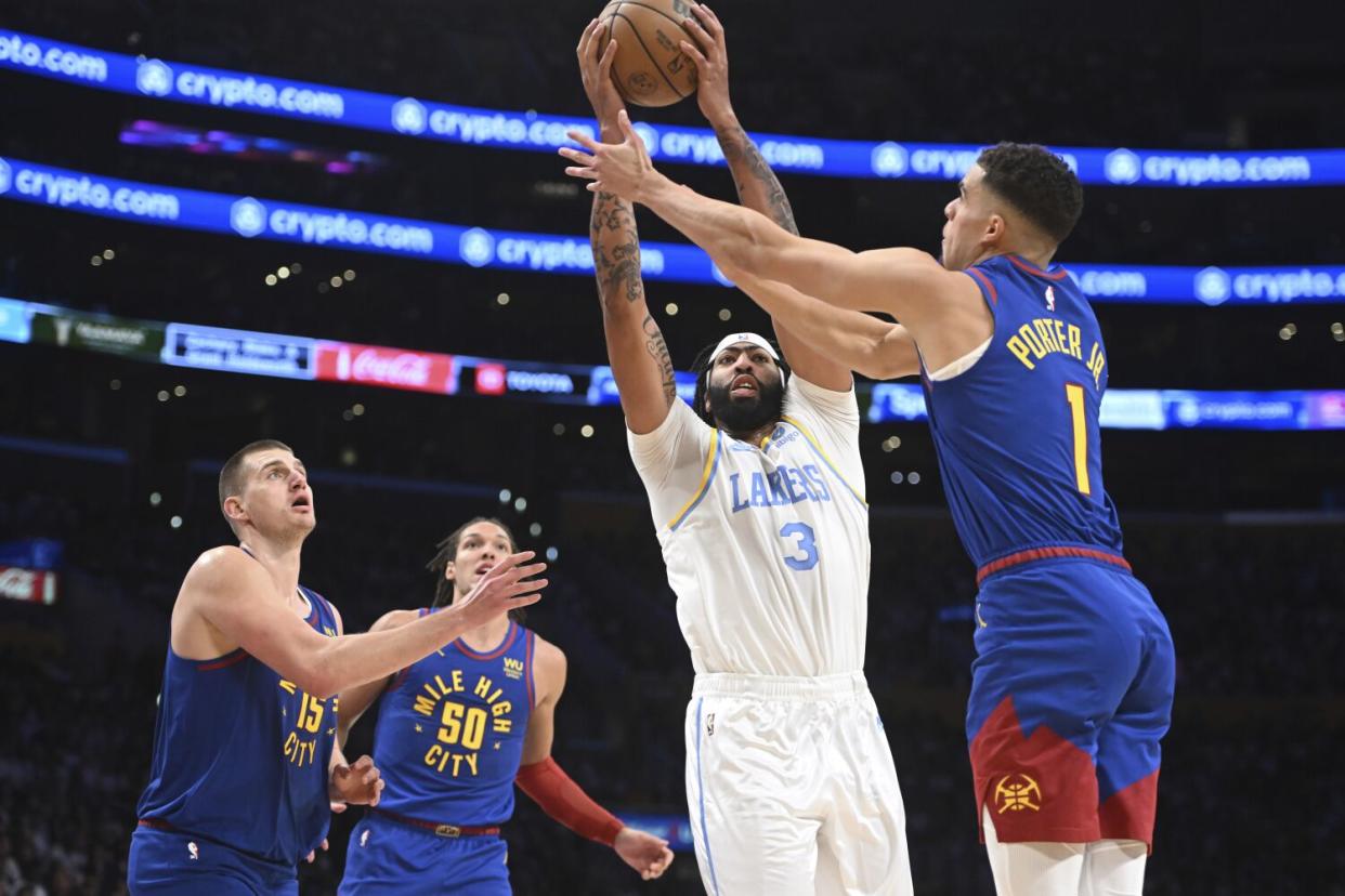 Lakers forward Anthony Davis grabs a rebound in front of Denver Nuggets forward Michael Porter Jr. during the first half.