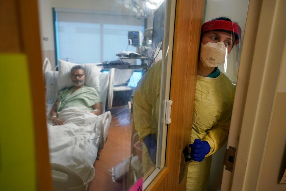 Registered nurse Rachel Chamberlin steps out of an isolation room where Fred Rutherford recovers from COVID-19 at Dartmouth-Hitchcock Medical Center, in Lebanon, N.H.