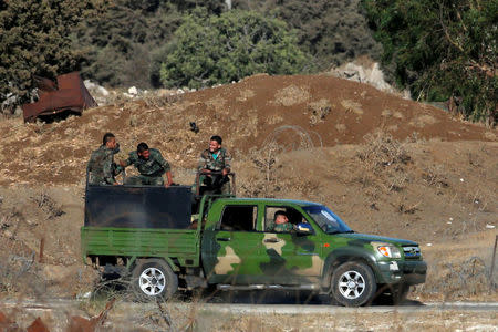 Uniformed men ride a pick up truck in Quneitra, on the Syrian side of the ceasefire line between Israel and Syria, as seen from the Israeli-occupied Golan Heights, July 26, 2018. REUTERS/Ammar Awad