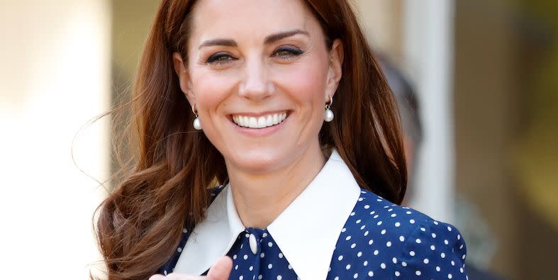 princess catherine of wales smiles and holds a bunch of flowers