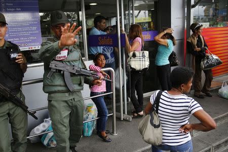 National guards stand at a supermarket entrance as people line up outside in Caracas January 19, 2015. REUTERS/Jorge Silva