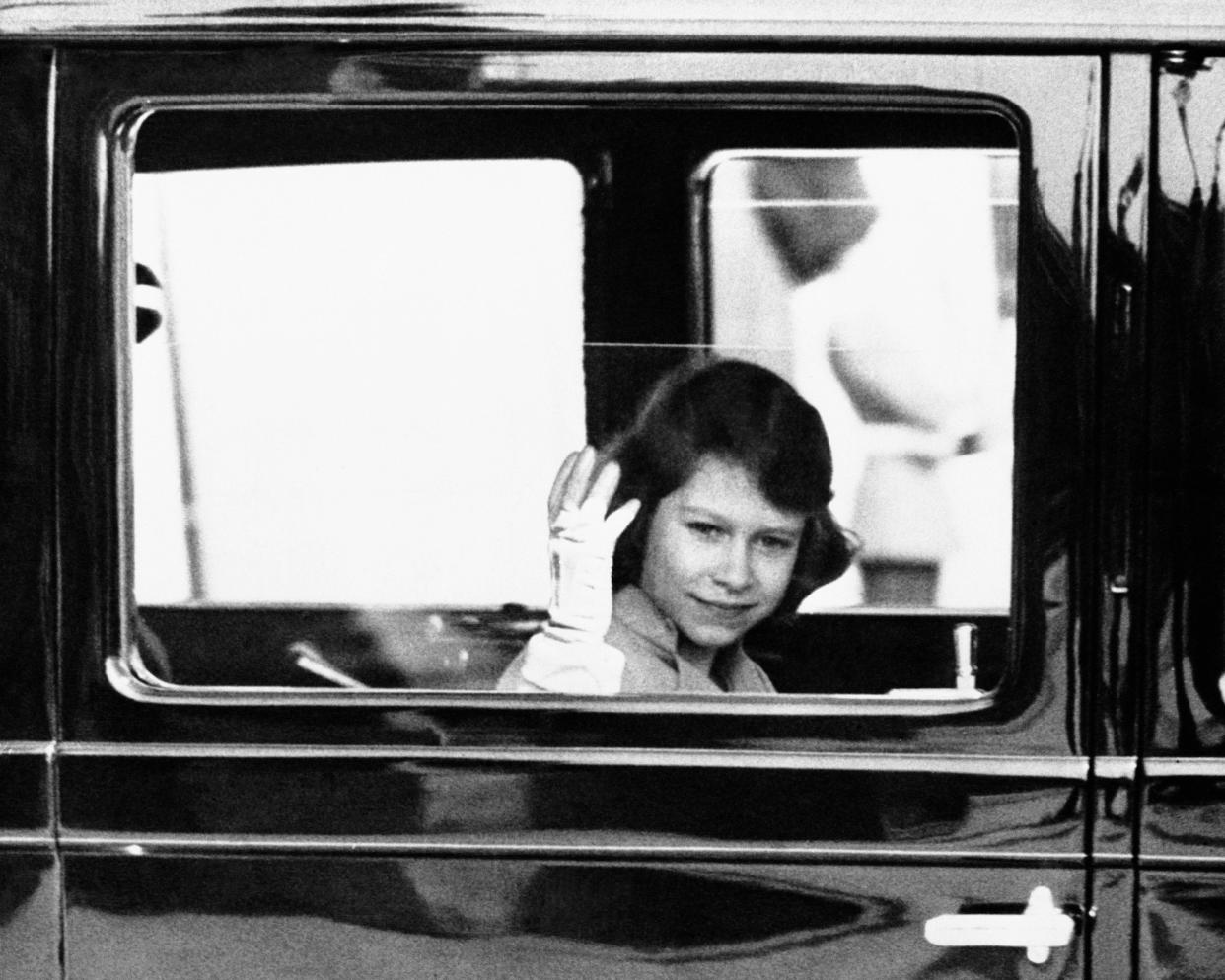 Princess Elizabeth, their-apparent to the throne of England as the king's oldest daughter, waves gracefully to the crowd which watched her leave Buckingham Palace by automobile on June 6, 1937 in London. 