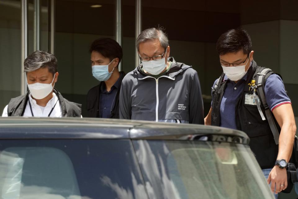 FILE - In this Thursday, June 17, 2021, file photo, police officers escort Cheung Kim-hung, center, CEO and Executive Director of Next Digital Ltd at Apple Daily headquarters in Hong Kong. Hong Kong's pro-democracy Apple Daily newspaper will close by this weekend after police arrested five editors and executives and froze $2.3 million in assets linked to the paper. (AP Photo/Kin Cheung, File)