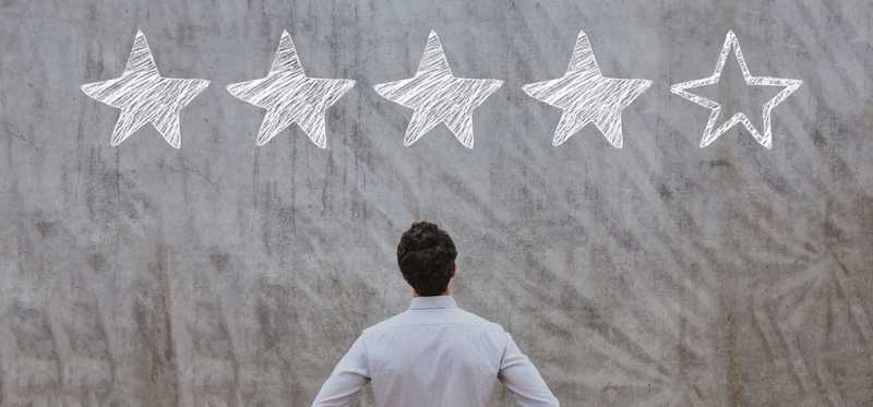 Man looking up at wall with 5 stars in chalk with 4 of them filled in.