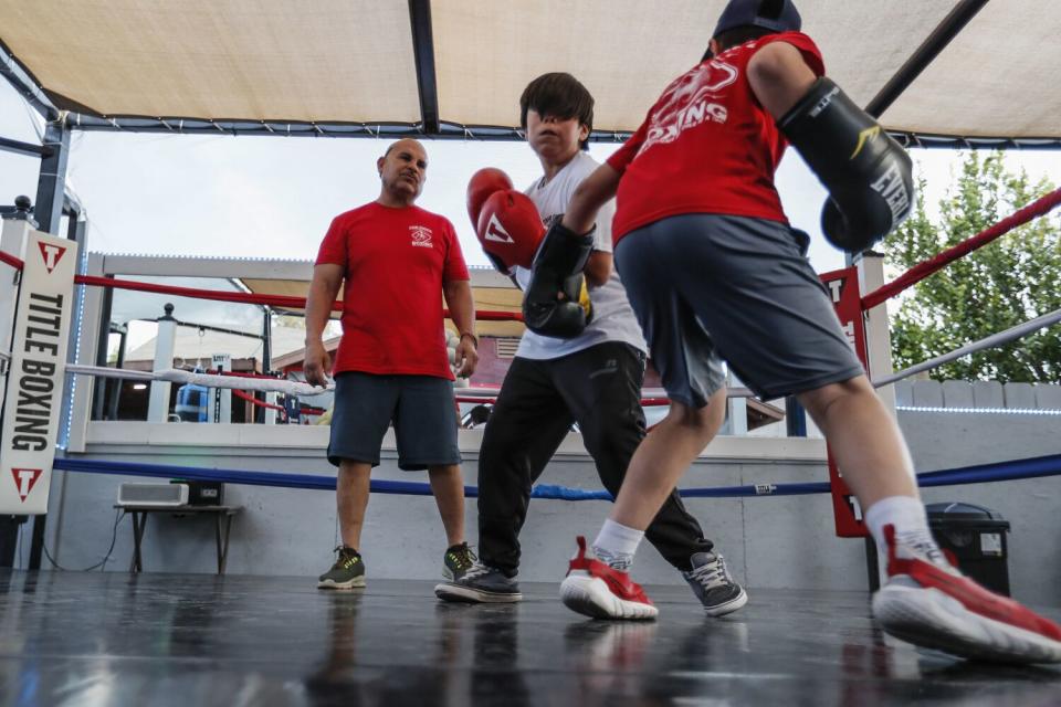 Former boxer Hector Lizarraga watches two young people box as he supervises.