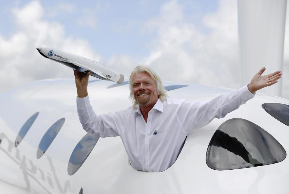 Entrepreneur Richard Branson waves a model of a LauncherOne cargo spacecraft from a window of an actual size model of SpaceShipTwo on display, after Virgin Galactic's LauncherOne announcement and news conference, at the Farnborough Airshow 2012 in southern England in this July 11, 2012 file photo. Delays in the launch of the first space flights by Sir Richard Branson's Virgin Galactic from a base in New Mexico have drawn criticism from a county commissioner in the south of the state. REUTERS/Luke MacGregor/Files (BRITAIN - Tags: TRANSPORT BUSINESS)