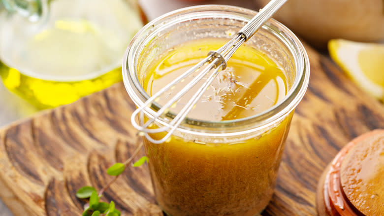 glass jar of vinaigrette with whisk