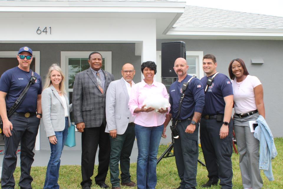 Consuela Green (middle) holds turkey gifted by the Palm Beach County Fire Rescue officers during the welcoming ceremony on Nov 17. attended by County Commissioner Melissa McKinlay (left) and Consuela's daughter (right).