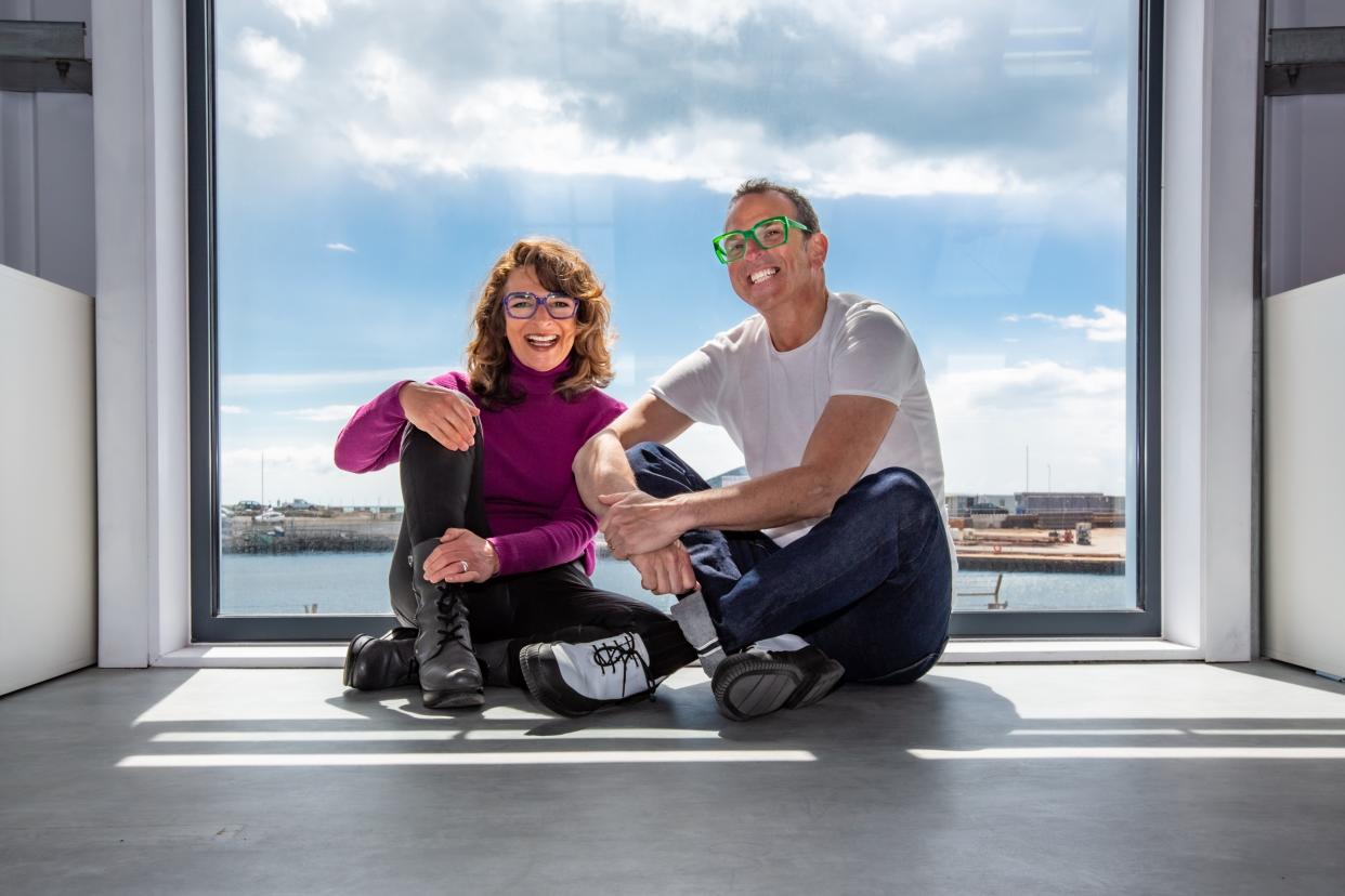 Woman and man wearing colourful glasses and sitting down