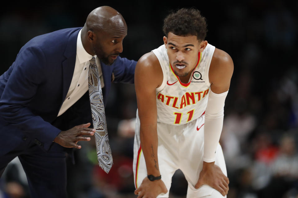 Atlanta Hawks head coach Lloyd Pierce, left, talks to Trae Young (11) in the first half of an NBA basketball game against the Philadelphia 76ers, Monday, Oct. 28, 2019, in Atlanta. (AP Photo/John Bazemore)