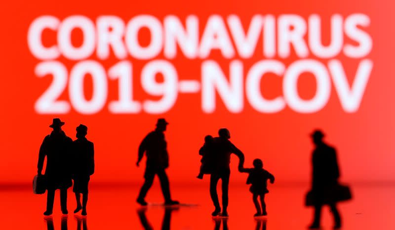 Small toy figures are seen in front of the coronavirus sign