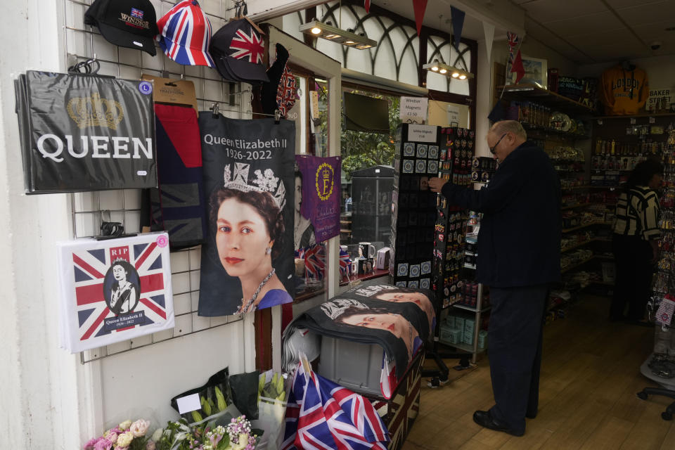 A man stops by a shop displaying various souvenirs of the late Queen Elizabeth II in Windsor, England, Thursday, Sept. 15, 2022. The Queen will lie in state in Westminster Hall for four full days before her funeral on Monday Sept. 19. (AP Photo/Gregorio Borgia)