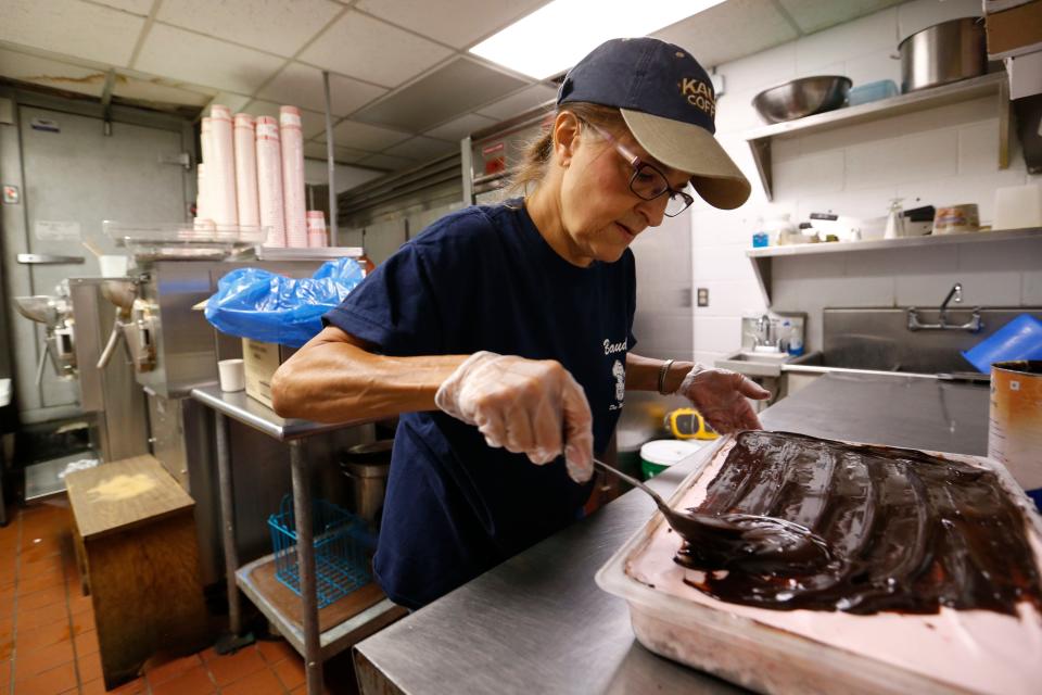 Kim Robertson, owner of Bauder's Ice Cream, spreads a layer of fudge over ice cream as she helps make the famed peppermint ice cream bars at Bauder's in Des Moines.