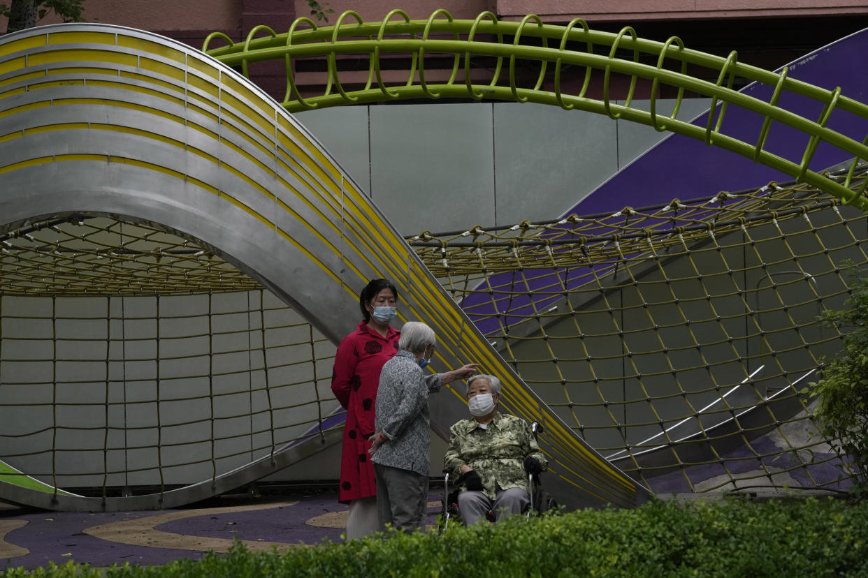 Residents wearing masks rest near an empty playground, Monday, June 13, 2022, in Beijing. (AP Photo/Ng Han Guan)