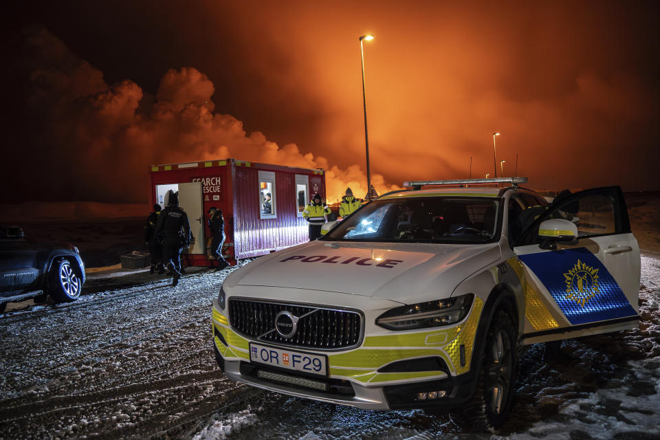 The police vehicle is parked at the entrance of the road to Grindavík with the eruption in the background, near Grindavik on Iceland’s Reykjanes Peninsula, Monday, Dec. 18, 2023. A volcanic eruption started Monday night on Iceland’s Reykjanes Peninsula, turning the sky orange and prompting the country’s civil defense to be on high alert. (AP Photo/Marco Di Marco)