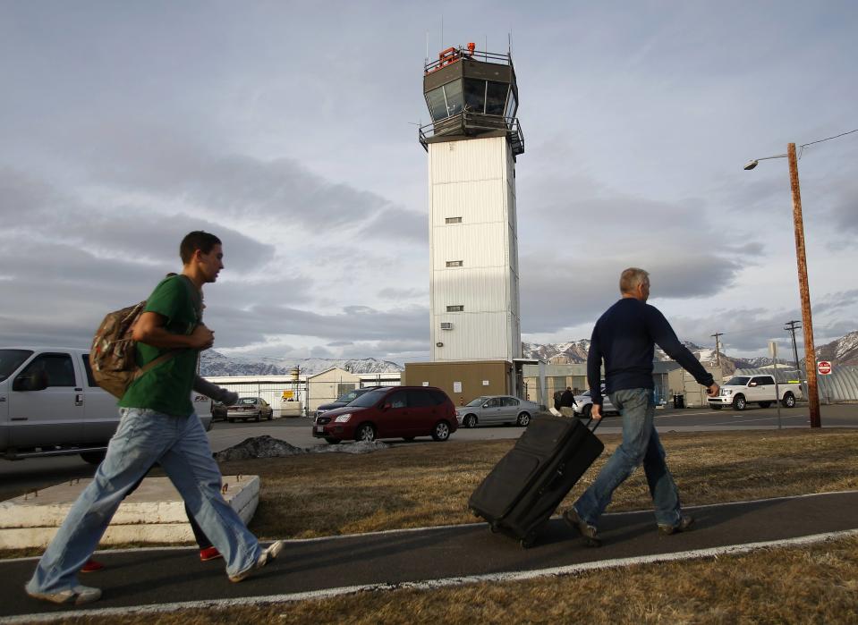 Airline passengers walk past an air traffic control tower at the Ogden-Hinckley Airport in Ogden, Utah in this file photo taken March 11, 2013. The U.S. air traffic control system is close to hitting a "yellow" alert level as people who keep radar and other equipment running remain out on furloughs due to the government shutdown, the head of the controllers union said on Thursday. (REUTERS/Jim Urquhart)