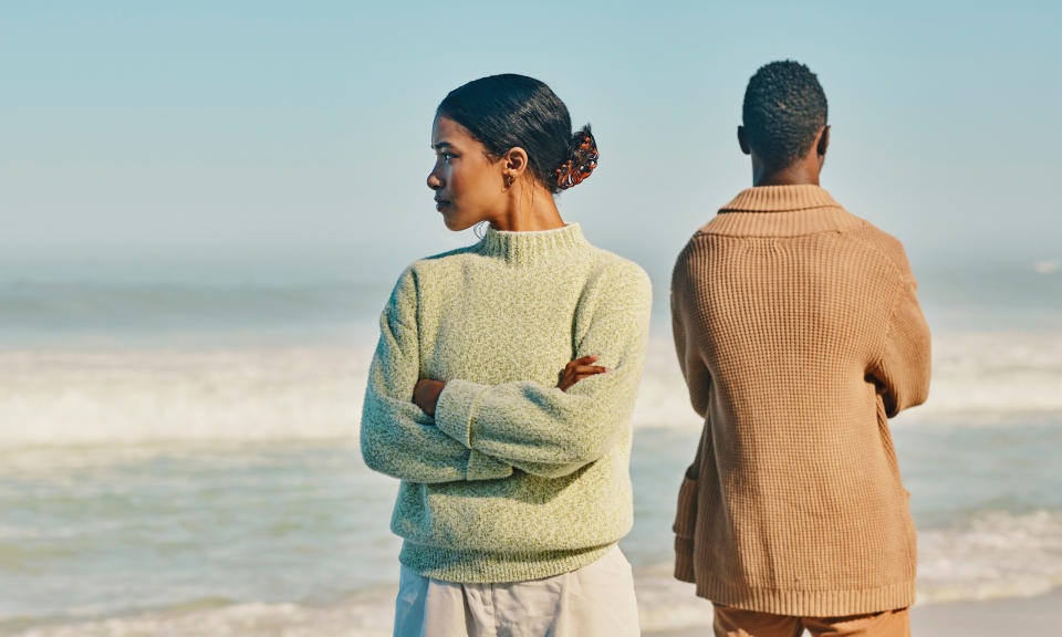 Female and male couple with backs turned against each other on a beach