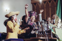 <p>Winnie Mandela, right, raises her fist to cheer the crowd as Jacqueline Jackson, wife of Jesse Jackson, left, applauds her during a church service on June 24, 1990, in Washington. The service honored South African women. (Photo: Jeff Markowitz/AP) </p>