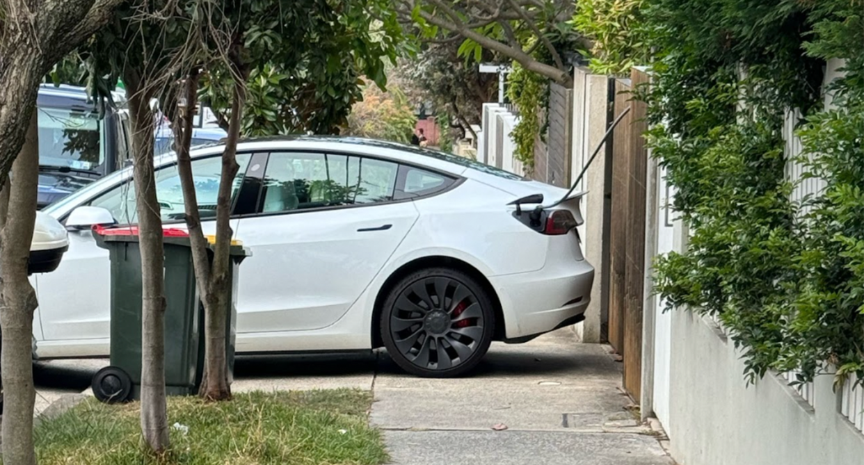 A Tesla parked across a suburban footpath in Sydney in order to charge the electric vehicle. 