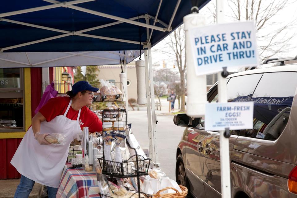 Rachel Heinsen grabs pastries for a customer at Great Harvest Bread Co., Tuesday, March 24, 2020 in Lafayette. The Kossuth Street bakery has utilized the shop's farmer's market tents to create a drive-thru in their parking lot.