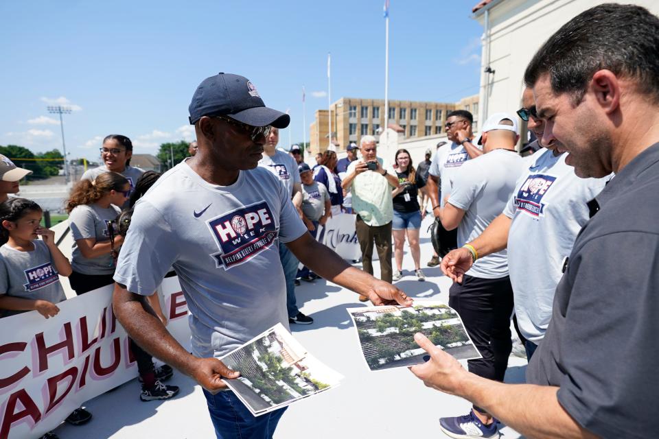 Baye Adofo-Wilson, CEO of BAW Development in charge of the Hinchliffe Stadium reconstruction, hands out photos of the stadium before construction.