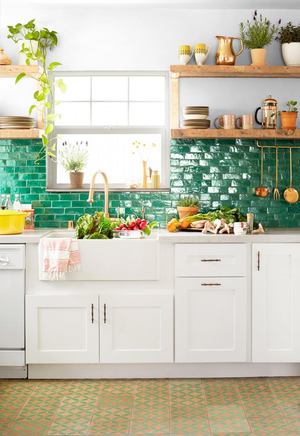 <p>Floating shelves are a great addition to pretty much any room in the house, but they seem to be a favorite in kitchens in particular. This is because they make it easier to grab items while you cook and clean than enclosed cabinets would, and they also give you an extra perch to display decor in an otherwise task-centric room. In Justina Blakeney's kitchen, the earthy, laidback reclaimed wood floating shelves are enhanced by the glossy forest green tile backslash. </p>