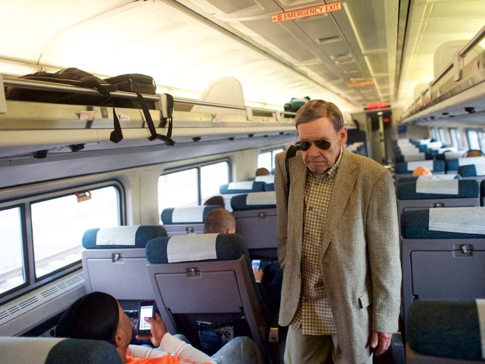 a man walking down the aisle of a crowded amtrak car