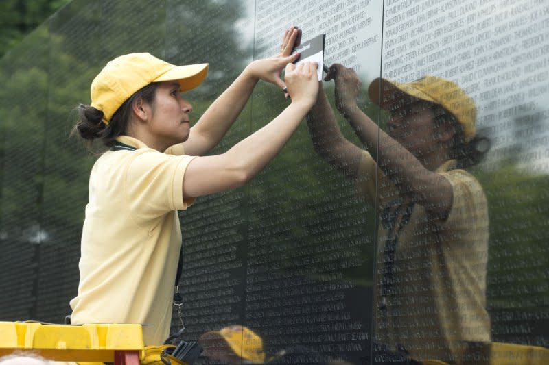 A volunteer helps a visitor etch the name of a loved one as thousands of people pay their respects at the Vietnam Veterans Memorial on the National Mall during Memorial Day weekend in Washington, D.C., May 27. On November 13, 1982, thousands of veterans of the Vietnam War march on Washington, D.C., to attend the dedication of the Vietnam Veterans Memorial. File Photo by Pat Benic/UPI