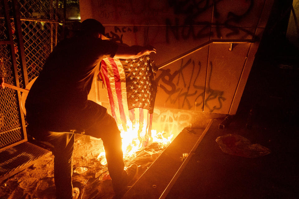 A Black Lives Matter protester burns an American flag outside the Mark O. Hatfield United States Courthouse on Monday, July 20, 2020, in Portland, Ore. Several hundred demonstrators gathered at the courthouse where federal officers deployed teargas and other crowd control munitions. (AP Photo/Noah Berger)