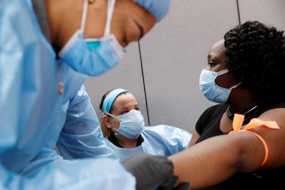 Clinicians take blood samples to look for coronavirus antibodies in a recovered COVID-19 patient.