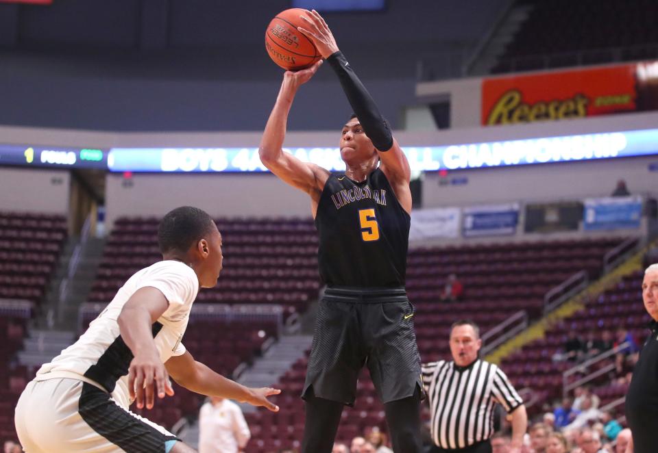 Lincoln Park's Meleek Thomas (5) shoots a three point shot after gaining space from Neumann-Goretti's Amir Ailliams (12) during the first half of the PIAA 4A Championship game Thursday night at the Giant Center in Hershey, PA.