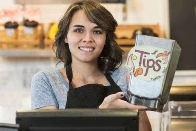 Young woman holding tip jar in cafe