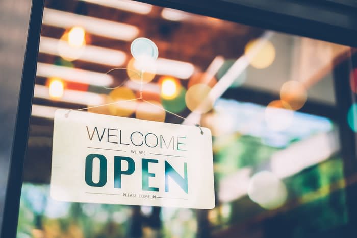 A sign that says the words welcome we are open hanging on a glass window.