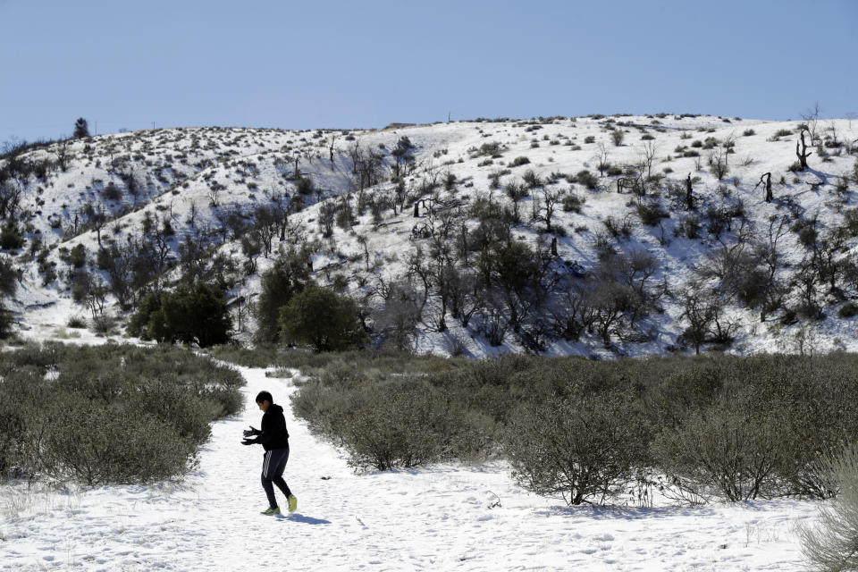 A young visitor walks along a snow covered trail Monday, Feb. 11, 2019, near Lebec, Calif. A series of winter storms socked the U.S west with unusual snow also falling in Hawaii and parts of Southern California. (AP Photo/Marcio Jose Sanchez)
