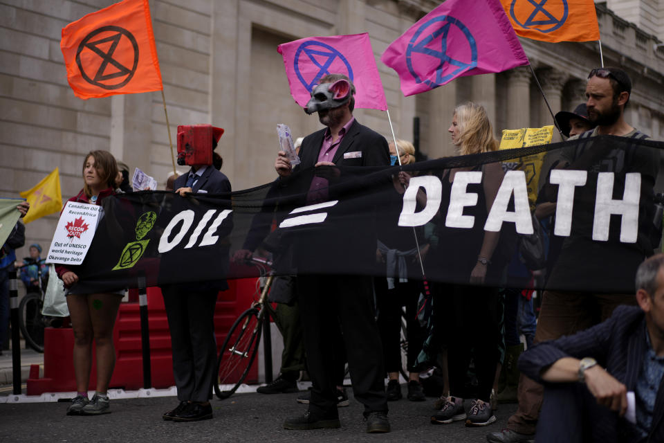 FILE - Extinction Rebellion climate change activists hold a banner during a protest backdropped by the Bank of England in London on Sept. 2, 2021. The U.K. division of climate change protest group Extinction Rebellion says its activists would temporarily stop blocking busy roads, gluing themselves to buildings and engaging in other acts of civil disobedience because such methods have not achieved their desired effects. (AP Photo/Matt Dunham, File)