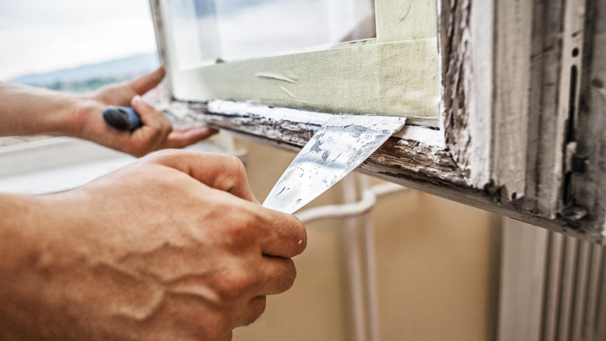 Man using scraper and putty for renovation old windows.