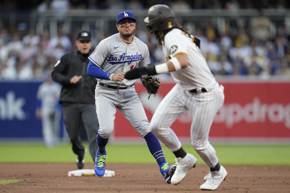 Los Angeles Dodgers shortstop Miguel Rojas, left, runs down San Diego Padres' Fernando Tatis Jr. before tagging him out on the fielder's choice hit by Juan Soto during the sixth inning of a baseball game Saturday, May 6, 2023, in San Diego. Soto was safe at first o the play. (AP Photo/Gregory Bull)